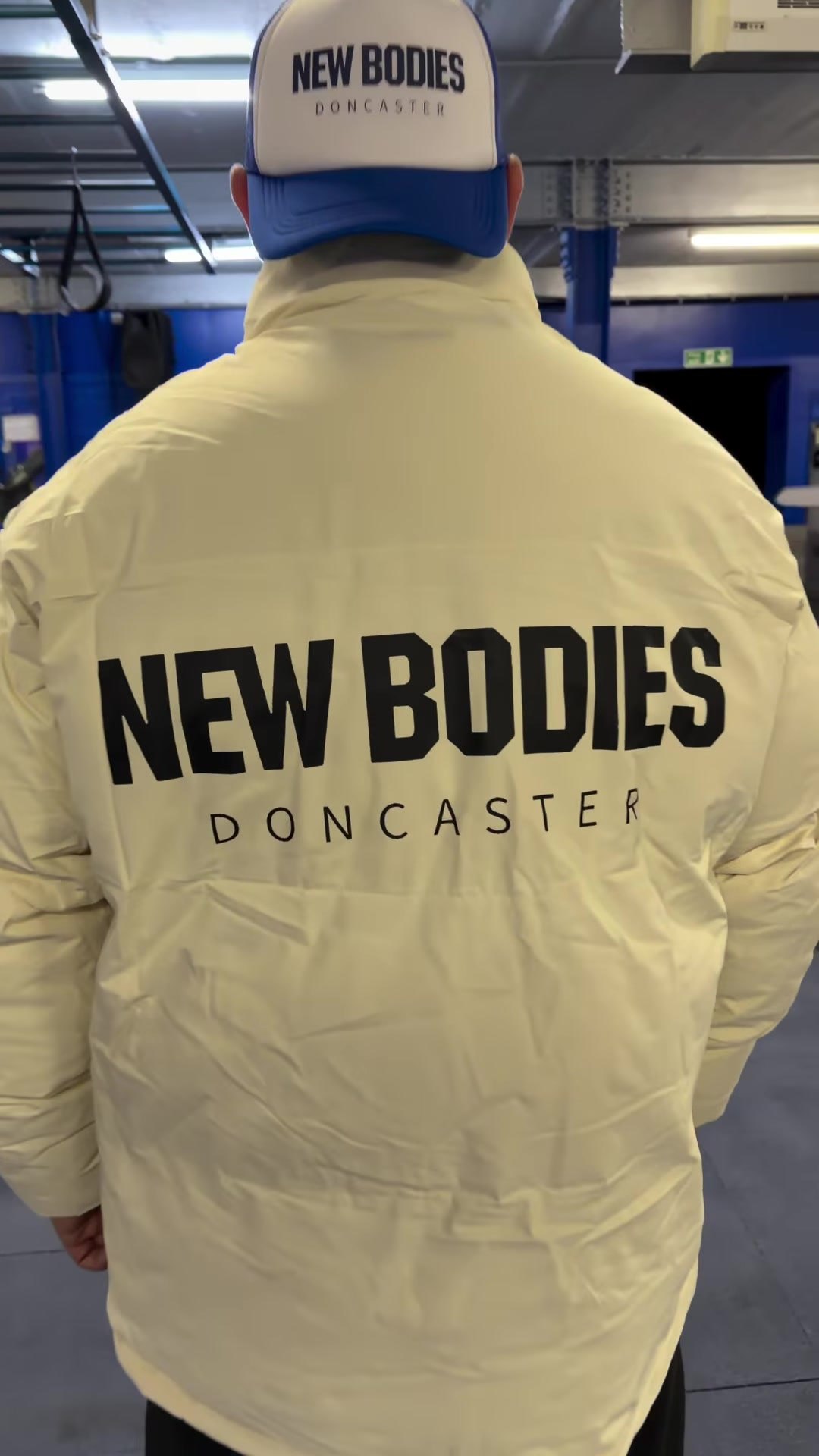 Back of a cream puffer jacket with a New Bodies Doncaster print
