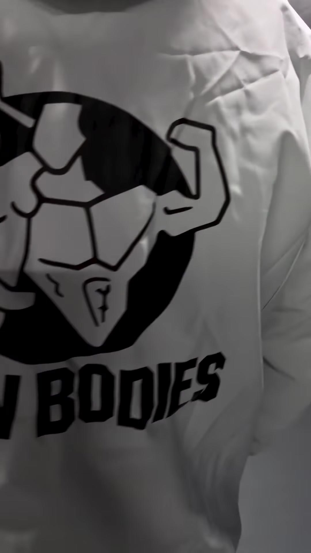 Close-up of the New Bodies logo printed on the back of a white wind breaker